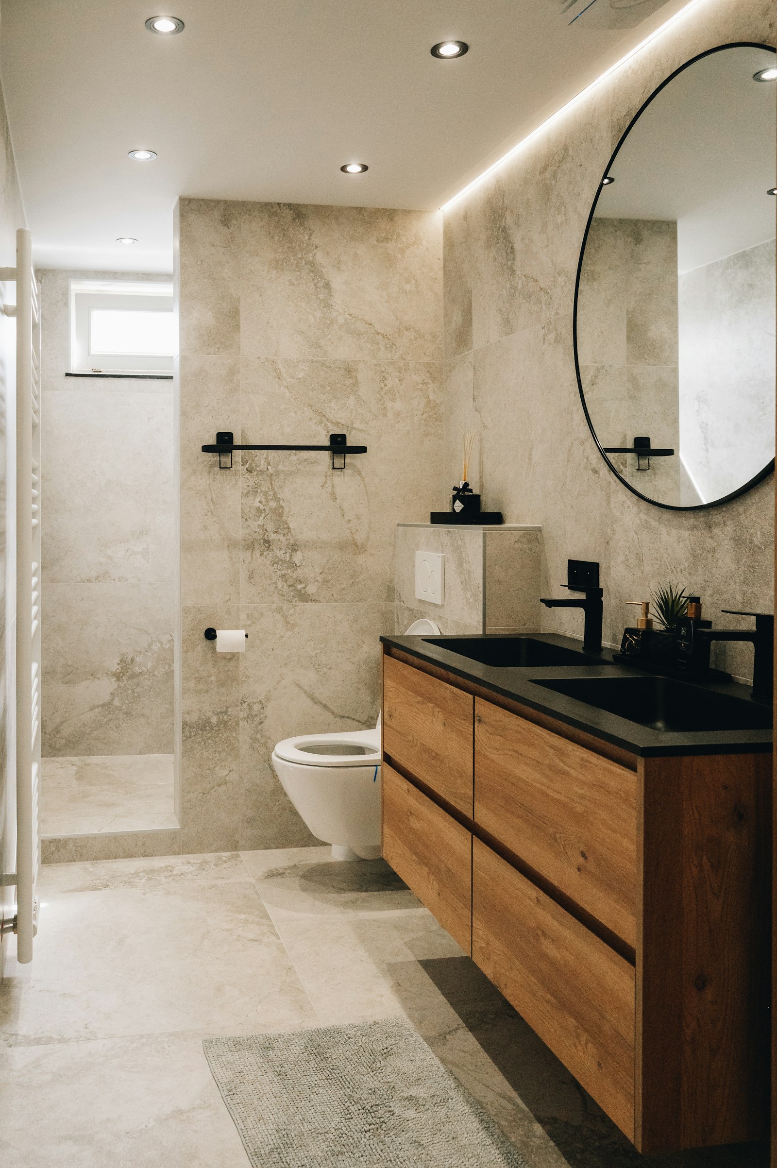 Baño moderno con mueble de madera, espejo redondo y acabados de piedra